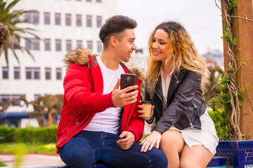 Fototapeta premium Lifestyle of a Caucasian couple doing vacation tourism, in a city park looking at things on the internet with the mobile
