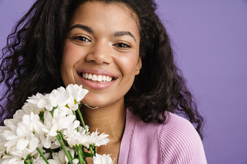 Young black woman smiling while posing with chrysanthemum