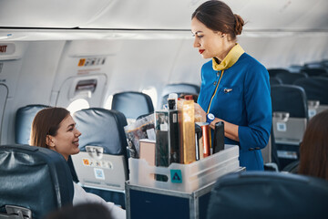 Woman on plane addressing flight attendant with food trolley