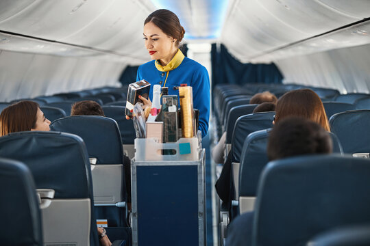 Female cabin crew showing package with coffee to woman traveller