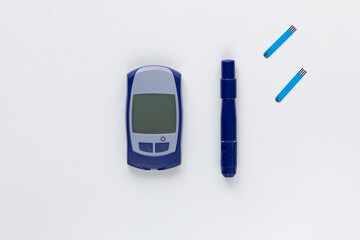 Top view of blood glucose meter, lancet and test strips on the white background