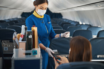 Airline stewardess holding terminal while passenger making payment