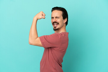 Young caucasian man isolated on blue background doing strong gesture