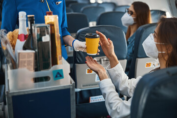 Flight hostess giving coffee cup to thankful passenger
