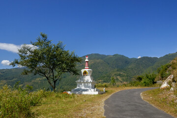 Fototapeta na wymiar Typical landscape view with chorten on the side of the road, Trashigang district, eastern Bhutan