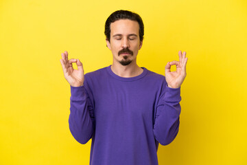 Young caucasian man isolated on yellow background in zen pose