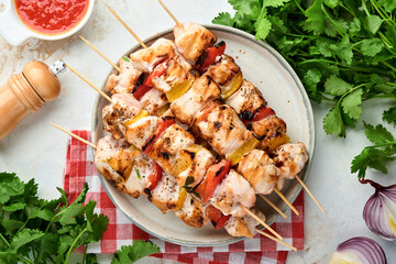 Chicken shish kebab or skewers kebab in a ceramic plate, spices, cilantro herbs and vegetables on...