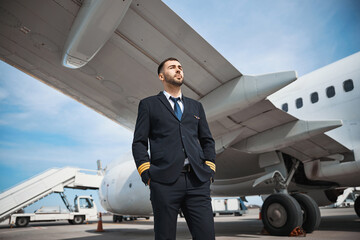 Confident pilot staring before himself near his plane