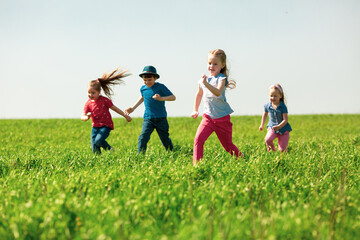 A group of happy children of boys and girls run in the Park on the grass on a Sunny summer day . The concept of ethnic friendship, peace, kindness, childhood