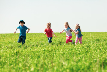 A group of happy children of boys and girls run in the Park on the grass on a Sunny summer day . The concept of ethnic friendship, peace, kindness, childhood