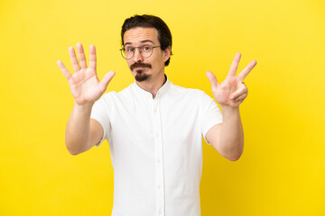 Young caucasian man isolated on yellow background counting eight with fingers