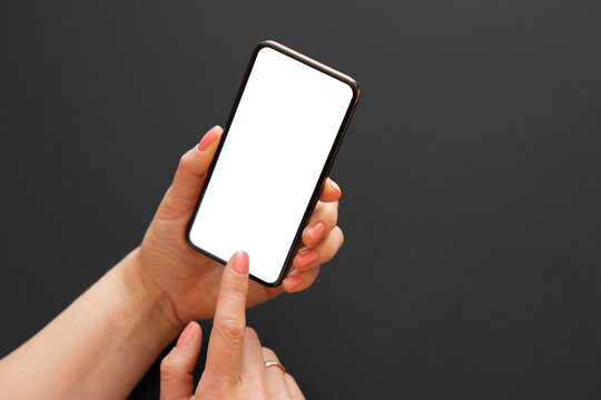 Person holding and using phone with empty white screen on dark background