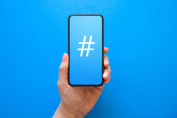 Person holding mobile phone with hashtag symbol on the screen