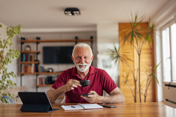Happy senior man, working from home office, drinking coffee.