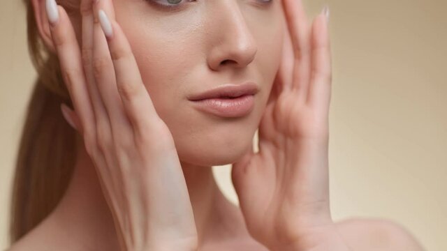 Close up shot of young unrecognizable caucasian woman touching her smooth cheeks, enjoying face skin condition
