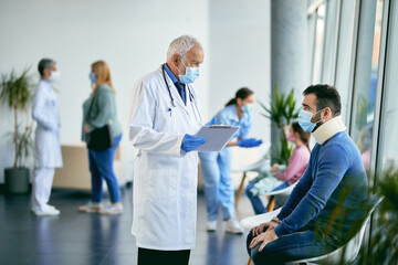 Obraz premium Senior doctor communicating with patient who is wearing neck collar in waiting room at the hospital.