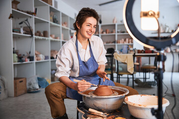 Cheerful ceramist smiling during work on clay product