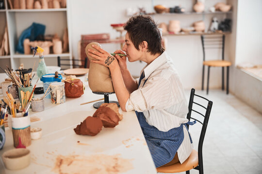 Pottery specialist making precise cuts with her modeling tool