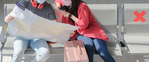 Two asian young traveler couple wearing face mask and discussing on mockup city map for plan...