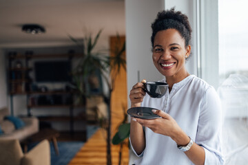 Smiling face, black woman, drinking tea at home.