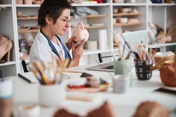 Pottery designer pointing at peace sign on tea mug bottom