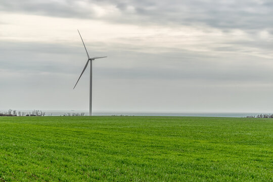 Wind Turbines Generating Electricity In A Green Field. Green Power Generation Concept.