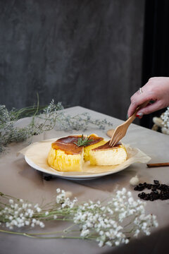 Cheese cake with a hand holding wooden folk and taking a piece of cake off.