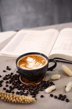 Latte art leaf and open book on the coffee table surrounded with coffee bean.