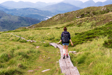 Woman walking on a mountain trail. Torc Mountain landscape in Killarney, Ireland.