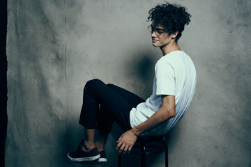 curly-haired guy sitting on a chair with glasses fashion studio