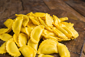 Small ravioli with cheese or meat to cook in broth, a traditional dish for celebrations in italy, Emilia Romagna region. Fresh homemade pasta with filling on a wooden table. Approaching from the top.