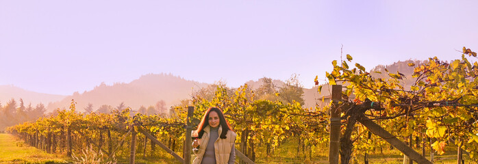 Young woman with a glass of white wine in the vineyards of Italy. Free space for text. Golden Autumn in the Hills Vineyards Tuscany region in italy. High quality photo. Copy space. Banner - obrazy, fototapety, plakaty