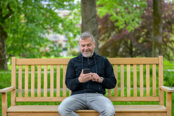 Fototapeta premium Happy relaxed middle-aged man using his mobile in a park