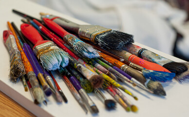 dirty brush set on the table. brushes with colorful paints displayed side by side. paint brushes with gouache on white