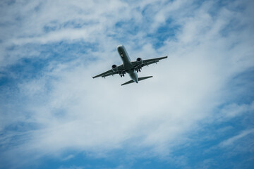 Fototapeta na wymiar Airplane flying through blue sky with puffy clouds.