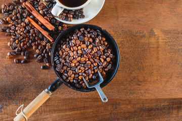 Top view of coffee beans roasted in a pan and a coffee cup.