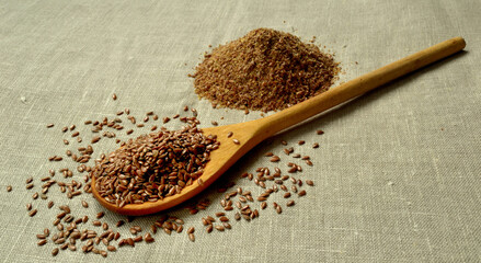 Whole and crushed flax seeds are on linen cloth
