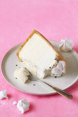 No-bake Cheesecake with Vanilla Panna Cotta decorated with Meringue Cookies, on a light pink background.