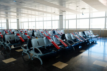 Airport terminal empty seats with red caution stickers as reminders to keep social distance. Preventive measures during coronavirus pandemic period. Close up, copy space for text, background.