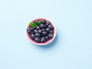 Bowl of fresh blueberries on a blue background