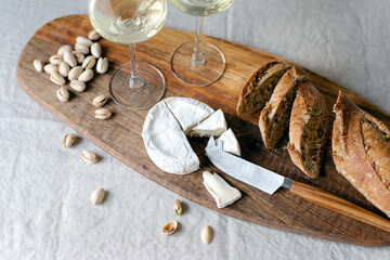 Two glasses of white wine and a wooden board with appetizers on the table.