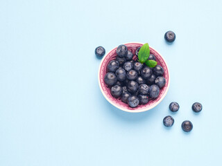 Bowl of fresh blueberries on a blue background