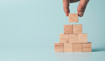 Hand putting and stacking blank wooden cubes on table with copy space for input wording and infographic icon.