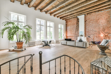 Big room with high wood beamed ceilings furnished with gray couch and art design elements in...