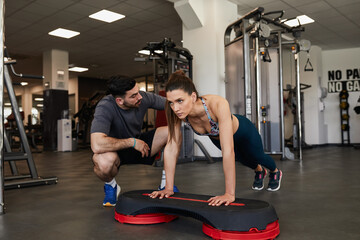 Fototapeta na wymiar Fit woman doing raised push up exercise with male trainer assistance
