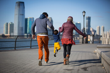 young couple with their kid walking by the river in New York