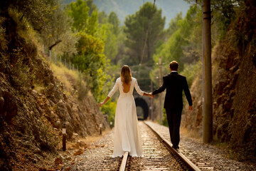 Bride and bridegroom walking on railroad tracks