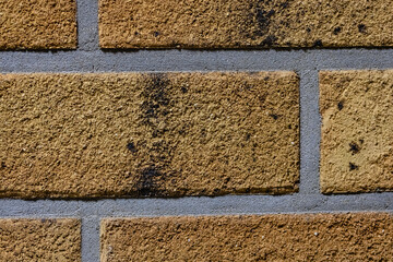 Close-up texture of a yellow scratched brick wall with a gray seam