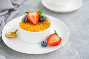 Creme brulee. Traditional French vanilla cream dessert with caramelised sugar and fresh berries on top.