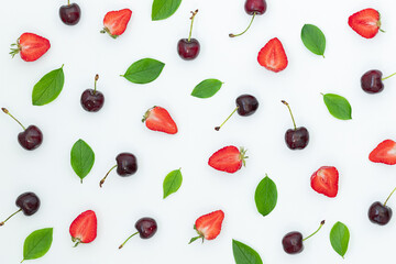 Summer bright background with strawberries, cherries and green leaves on gray surface